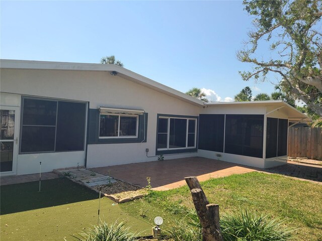 860 Bruce Ave, Clearwater Beach, FL 33767 - back of property with a sunroom, a putting area, a patio, and stucco siding