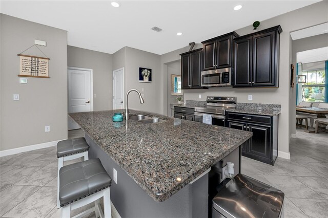 11320 Chilly Water Ct, Riverview, FL 33569 - kitchen featuring appliances with stainless steel finishes, a sink, a kitchen breakfast bar, dark cabinetry, and dark stone counters