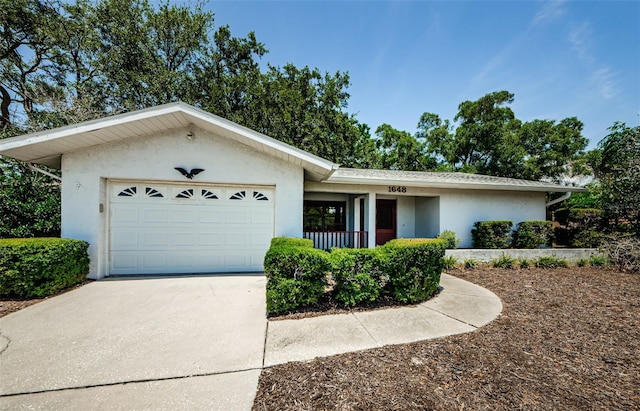 1648 Concord St, Dunedin, FL 34698 - single story home with stucco siding, an attached garage, concrete driveway, and covered porch