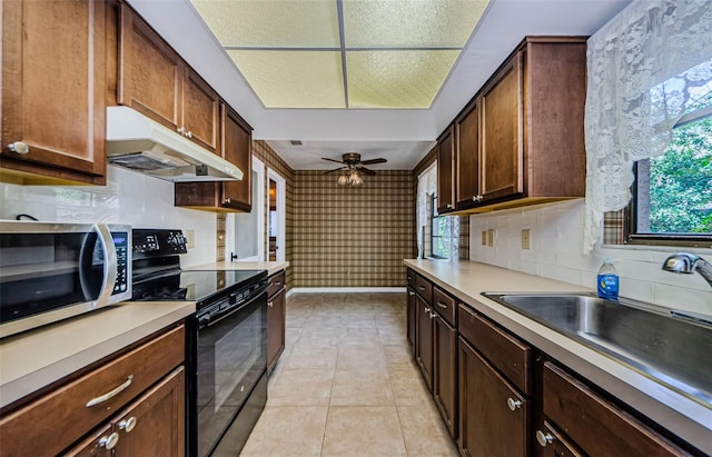 1648 Concord St, Dunedin, FL 34698 - kitchen with black range with electric cooktop, stainless steel microwave, under cabinet range hood, light tile patterned flooring, and tasteful backsplash