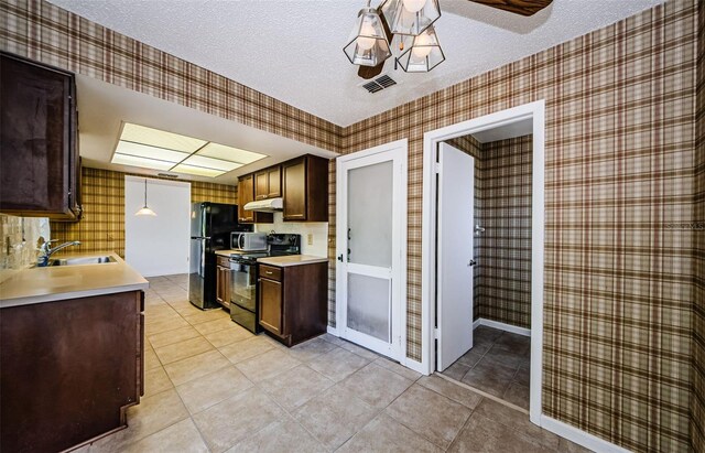 1648 Concord St, Dunedin, FL 34698 - kitchen featuring black appliances, wallpapered walls, a textured ceiling, under cabinet range hood, and light tile patterned floors