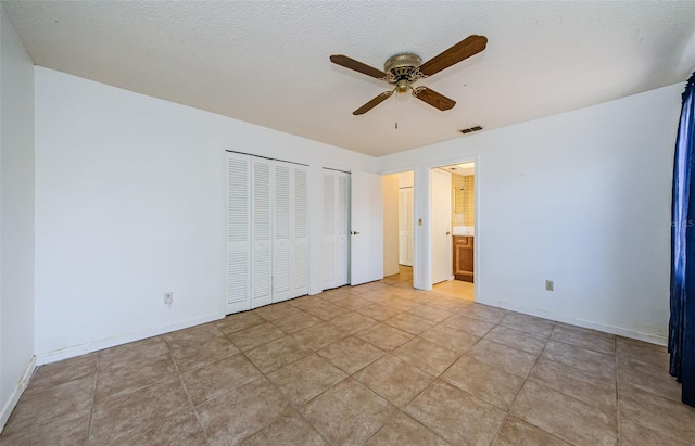 1648 Concord St, Dunedin, FL 34698 - unfurnished bedroom featuring multiple closets, baseboards, connected bathroom, and a ceiling fan