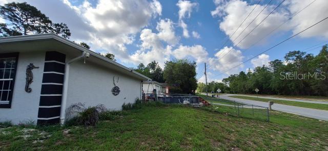 1160 W Geneva Pl, Citrus Springs, FL 34434 - view of side of home with stucco siding and a yard