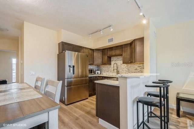 4325 58th Way N Unit 1527, Kenneth City, FL 33709 - kitchen featuring stainless steel fridge with ice dispenser, a breakfast bar, light countertops, a peninsula, and light wood-type flooring
