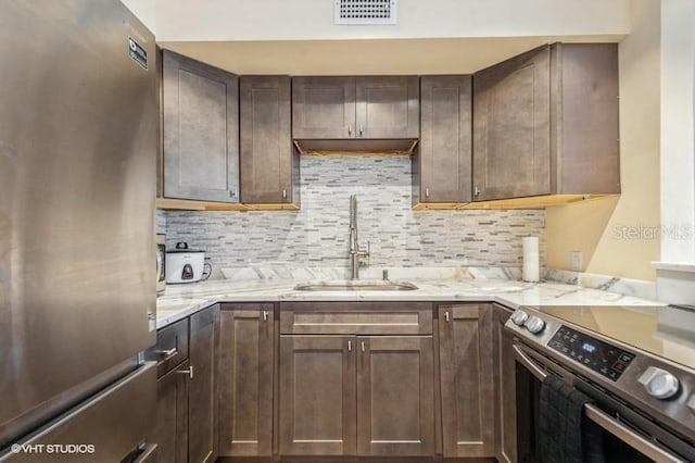 4325 58th Way N Unit 1527, Kenneth City, FL 33709 - kitchen featuring appliances with stainless steel finishes, a sink, tasteful backsplash, dark brown cabinetry, and light stone countertops