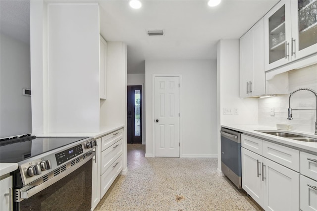 4400 Helena St NE, Saint Petersburg, FL 33703 - kitchen with stainless steel appliances, a sink, decorative backsplash, dark aggregate flooring, and white cabinetry