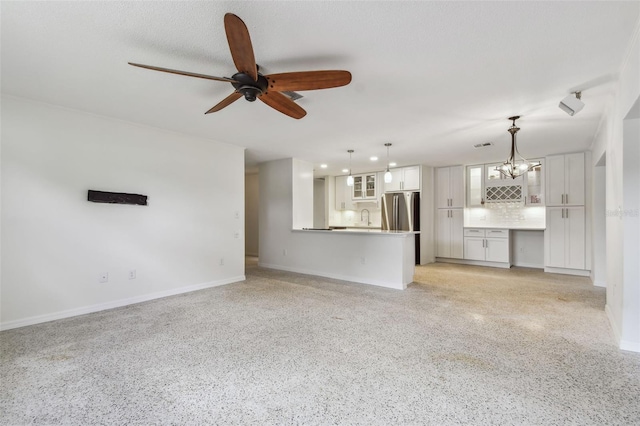 4400 Helena St NE, Saint Petersburg, FL 33703 - unfurnished living room featuring a ceiling fan, baseboards, a sink, dark speckled floor, and a chandelier