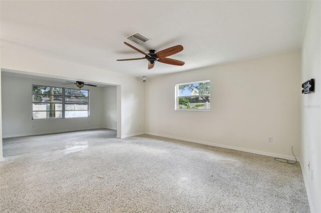 4400 Helena St NE, Saint Petersburg, FL 33703 - empty room with healthy amount of natural light, speckled floor, ceiling fan, and baseboards
