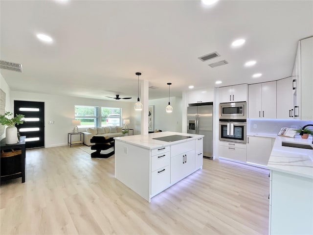 1290 Michigan Blvd, Dunedin, FL 34698 - kitchen featuring appliances with stainless steel finishes, a kitchen island, open floor plan, light wood-style floors, and white cabinets