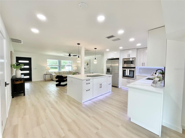 1290 Michigan Blvd, Dunedin, FL 34698 - kitchen with appliances with stainless steel finishes, open floor plan, a center island, decorative light fixtures, and light countertops