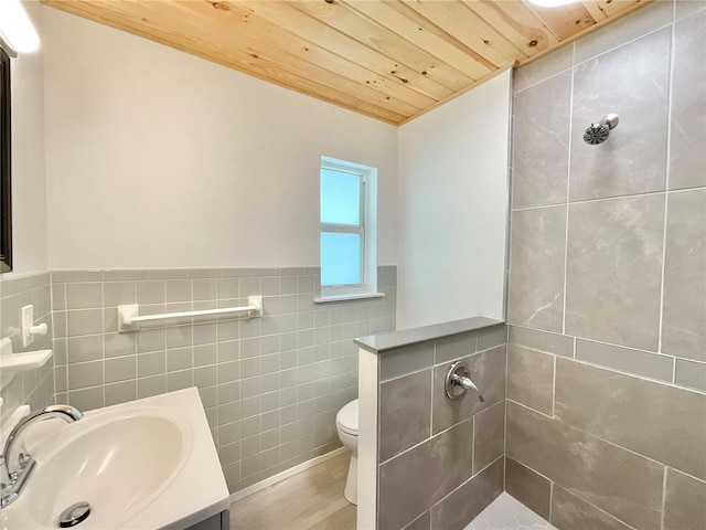 1290 Michigan Blvd, Dunedin, FL 34698 - bathroom with tile walls, wood ceiling, a tile shower, a wainscoted wall, and vanity