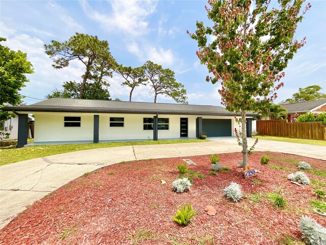 1290 Michigan Blvd, Dunedin, FL 34698 - view of front facade with curved driveway, an attached garage, and stucco siding
