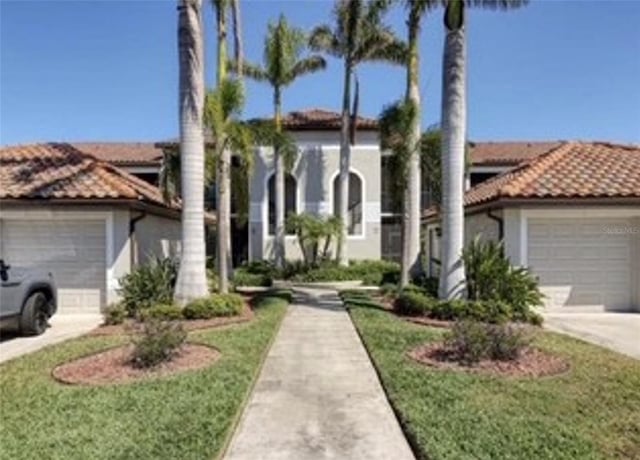6715 Grand Estuary Trl Unit 203, Bradenton, FL 34212 - mediterranean / spanish-style home with an attached garage, a tiled roof, driveway, and stucco siding