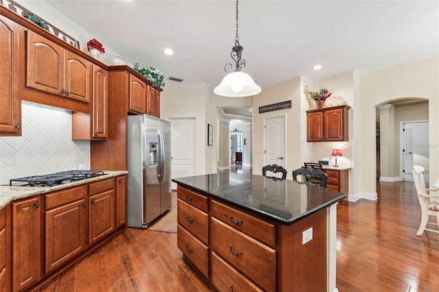 16039 Ternglade Dr, Lithia, FL 33547 - kitchen with stainless steel refrigerator with ice dispenser, black gas cooktop, arched walkways, decorative backsplash, and dark wood-style flooring