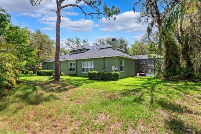 16039 Ternglade Dr, Lithia, FL 33547 - rear view of house with a chimney, stucco siding, a lawn, a lanai, and roof with shingles