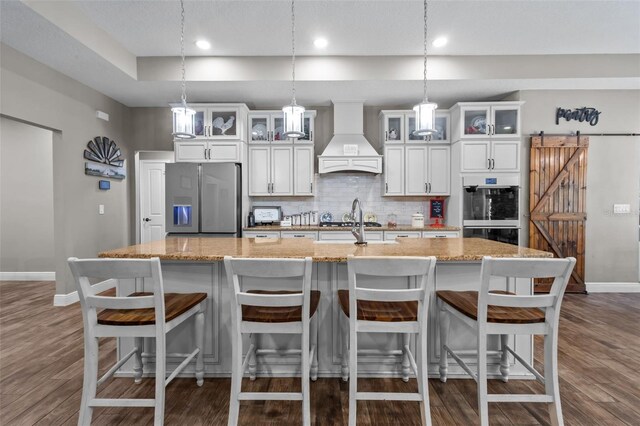 12090 Thames Ave, Weeki Wachee, FL 34614 - kitchen with custom exhaust hood, stainless steel fridge, double oven, baseboards, and a spacious island