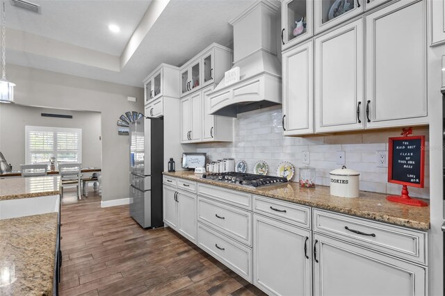 12090 Thames Ave, Weeki Wachee, FL 34614 - kitchen featuring appliances with stainless steel finishes, custom exhaust hood, white cabinetry, backsplash, and dark wood-type flooring