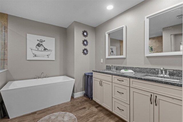 12090 Thames Ave, Weeki Wachee, FL 34614 - full bath featuring a freestanding bath, double vanity, wood finished floors, and baseboards
