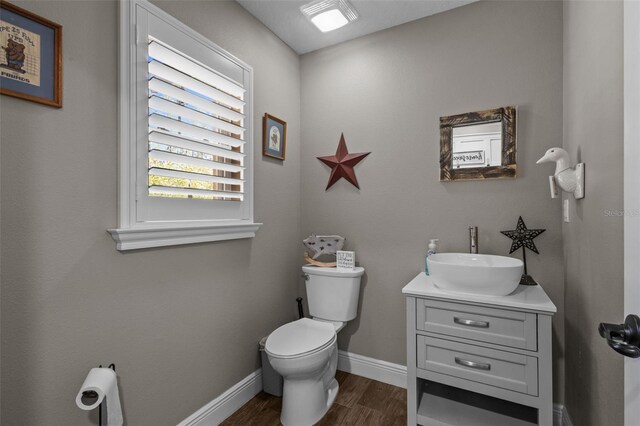 12090 Thames Ave, Weeki Wachee, FL 34614 - bathroom featuring toilet, vanity, wood finished floors, and baseboards