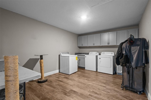 12090 Thames Ave, Weeki Wachee, FL 34614 - laundry room with cabinet space, independent washer and dryer, light wood-style flooring, baseboards, and a textured ceiling