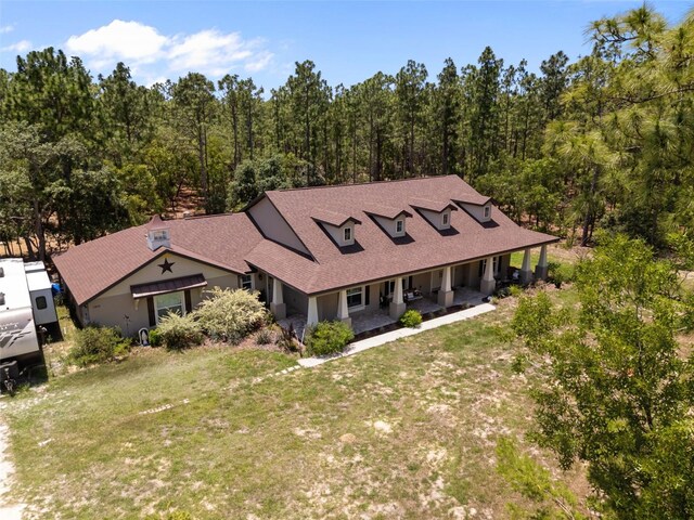 12090 Thames Ave, Weeki Wachee, FL 34614 - view of front of property featuring covered porch, a front lawn, a view of trees, and a shingled roof