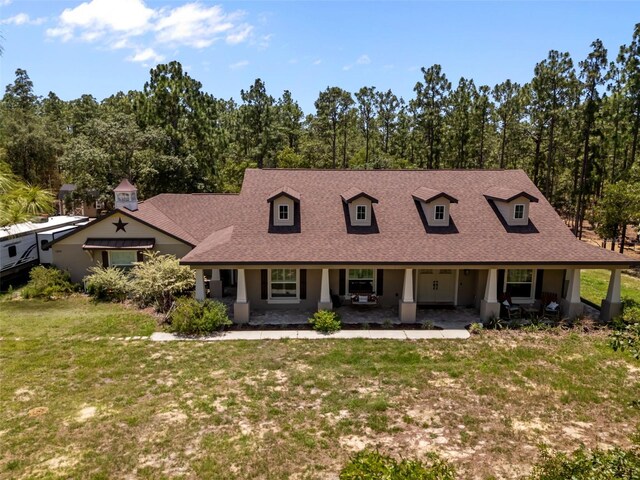 12090 Thames Ave, Weeki Wachee, FL 34614 - view of front of home with a porch, a shingled roof, and a front lawn