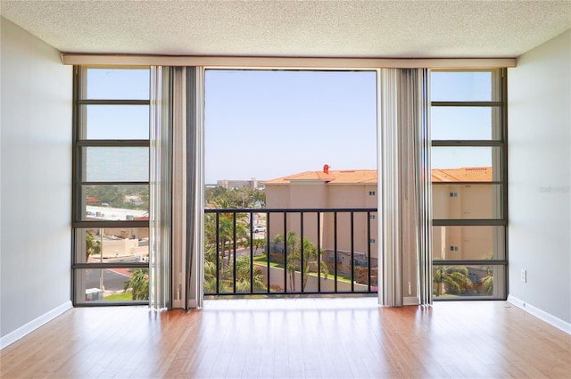 7400 Sun Island Dr S Unit 501, South Pasadena, FL 33707 - unfurnished room with wood-type flooring, baseboards, a textured ceiling, and expansive windows