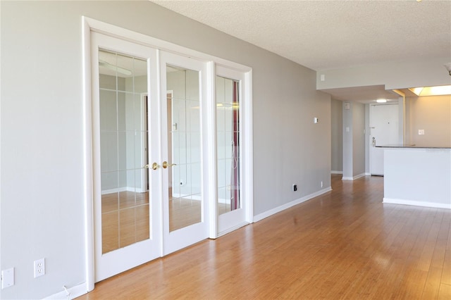 7400 Sun Island Dr S Unit 501, South Pasadena, FL 33707 - empty room with french doors, light wood-style flooring, baseboards, and a textured ceiling