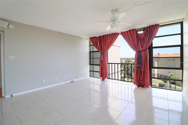 7400 Sun Island Dr S Unit 501, South Pasadena, FL 33707 - spare room featuring a ceiling fan, baseboards, expansive windows, a textured ceiling, and tile patterned floors