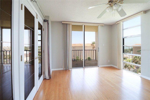 7400 Sun Island Dr S Unit 501, South Pasadena, FL 33707 - empty room featuring light wood-type flooring, a textured ceiling, ceiling fan, baseboards, and expansive windows