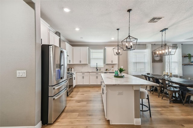 17589 Cruiser Bnd, Land O Lakes, FL 34638 - kitchen featuring appliances with stainless steel finishes, a center island, a kitchen bar, white cabinetry, and tasteful backsplash