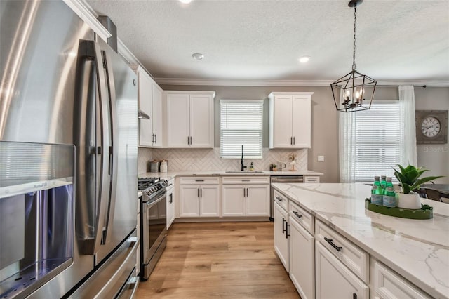 17589 Cruiser Bnd, Land O Lakes, FL 34638 - kitchen featuring stainless steel appliances, a sink, white cabinetry, a chandelier, and crown molding