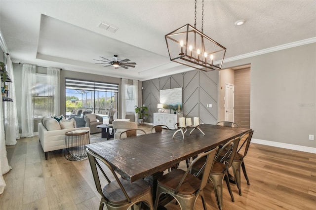 17589 Cruiser Bnd, Land O Lakes, FL 34638 - dining area featuring baseboards, light wood-style flooring, a tray ceiling, ceiling fan, and crown molding