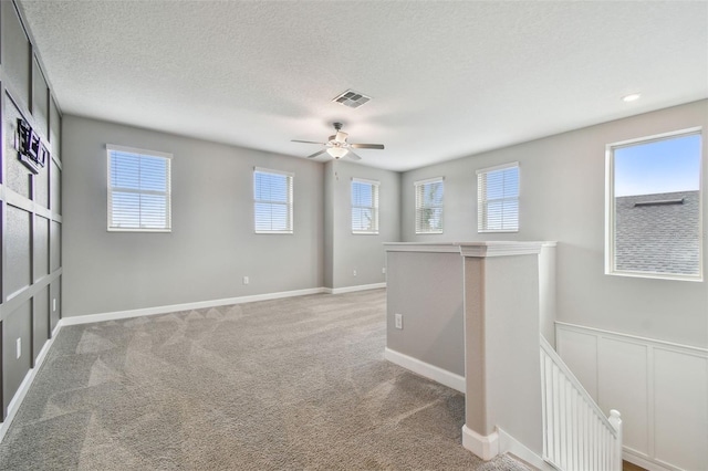 17589 Cruiser Bnd, Land O Lakes, FL 34638 - unfurnished room with plenty of natural light, a ceiling fan, light colored carpet, and a textured ceiling