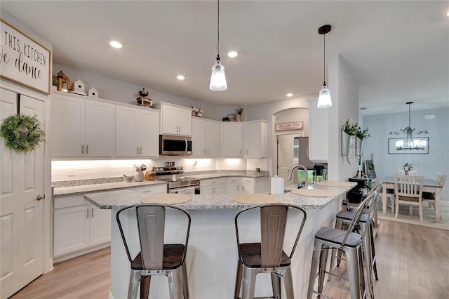 4435 Devinshire Fields Loop, Plant City, FL 33567 - kitchen featuring appliances with stainless steel finishes, white cabinetry, a kitchen breakfast bar, light wood-type flooring, and recessed lighting