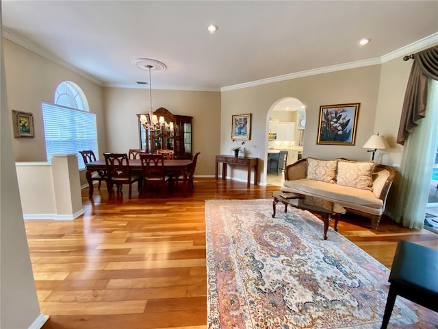 4808 Jewell Ter, Palm Harbor, FL 34685 - living room with arched walkways, crown molding, light wood-type flooring, a chandelier, and baseboards