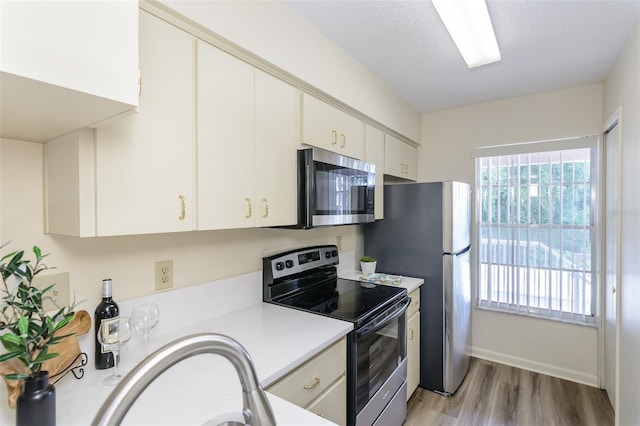 6334 Spring Flower Dr Unit 24, New Port Richey, FL 34653 - kitchen featuring appliances with stainless steel finishes, light wood-type flooring, light countertops, white cabinetry, and baseboards