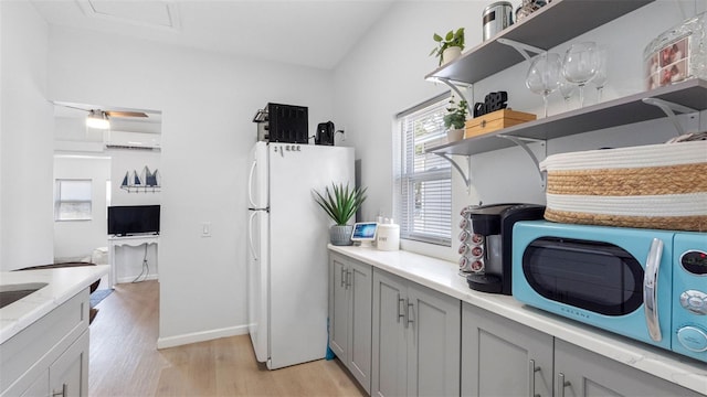 1615 28th Ave N, Saint Petersburg, FL 33713 - kitchen featuring gray cabinetry, light wood-type flooring, freestanding refrigerator, and open shelves
