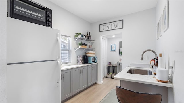 1615 28th Ave N, Saint Petersburg, FL 33713 - kitchen featuring freestanding refrigerator, a sink, gray cabinets, light wood-type flooring, and stainless steel microwave
