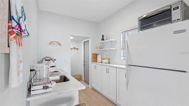 1615 28th Ave N, Saint Petersburg, FL 33713 - kitchen featuring freestanding refrigerator, white cabinets, light countertops, light wood-style floors, and a sink