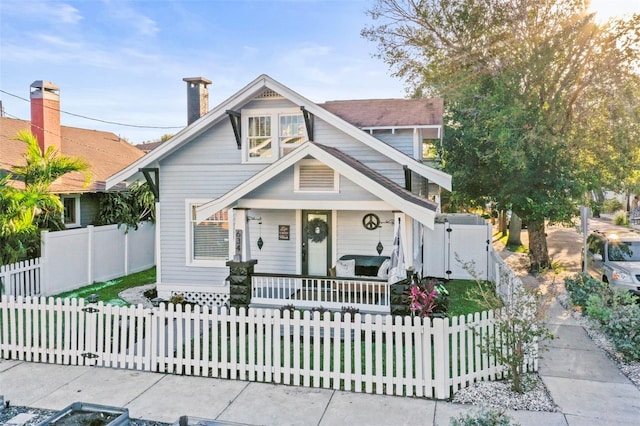 634 6th St N, Saint Petersburg, FL 33701 - view of front of house featuring a porch, a chimney, and a fenced front yard