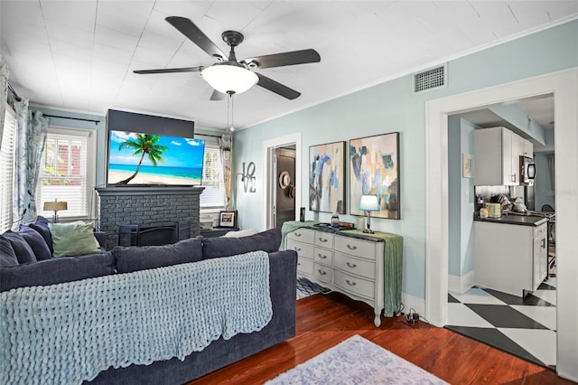 634 6th St N, Saint Petersburg, FL 33701 - living room with ceiling fan, crown molding, wood finished floors, a brick fireplace, and baseboards