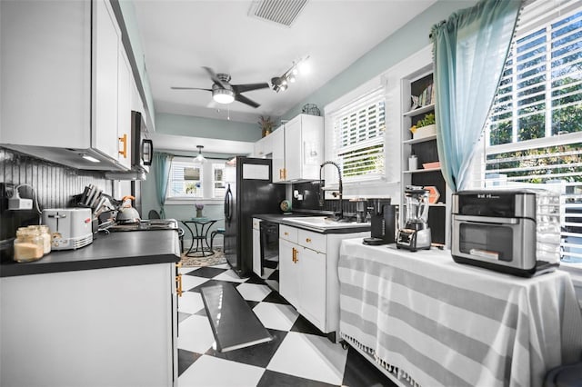 634 6th St N, Saint Petersburg, FL 33701 - kitchen featuring a sink, dark floors, dark countertops, a ceiling fan, and white cabinets