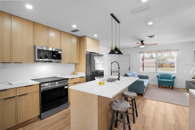 1851 Oklahoma Ave NE, Saint Petersburg, FL 33703 - kitchen with stainless steel appliances, open floor plan, a kitchen bar, light wood finished floors, and a sink
