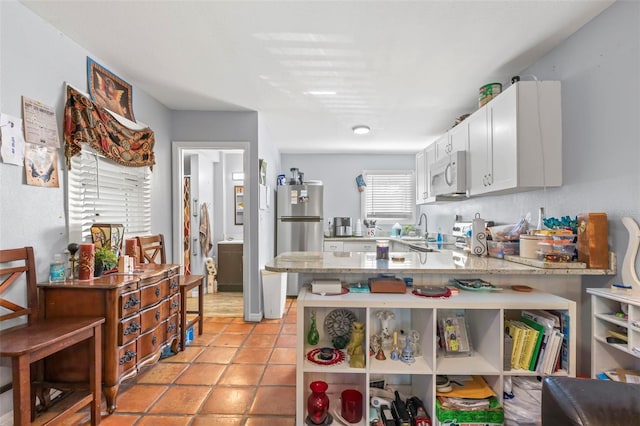 1115 Highland St N, Saint Petersburg, FL 33701 - kitchen with white microwave, freestanding refrigerator, white cabinetry, a peninsula, and light tile patterned floors