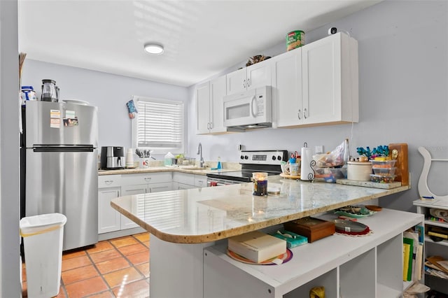 1115 Highland St N, Saint Petersburg, FL 33701 - kitchen featuring appliances with stainless steel finishes, a peninsula, white cabinets, a sink, and light tile patterned floors