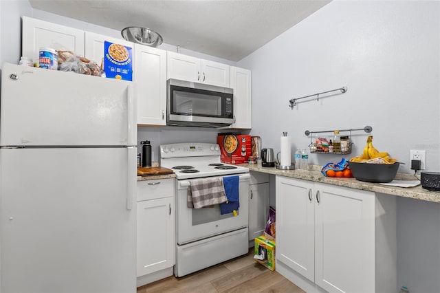 1115 Highland St N, Saint Petersburg, FL 33701 - kitchen with white appliances, light wood-style flooring, and white cabinets