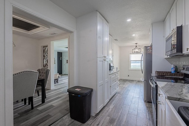 1816 W Lake Parker Dr, Lakeland, FL 33805 - kitchen with appliances with stainless steel finishes, white cabinets, wood finished floors, a textured ceiling, and recessed lighting