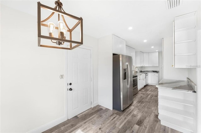 1816 W Lake Parker Dr, Lakeland, FL 33805 - kitchen featuring stainless steel appliances, wood finished floors, white cabinetry, recessed lighting, and light stone counters