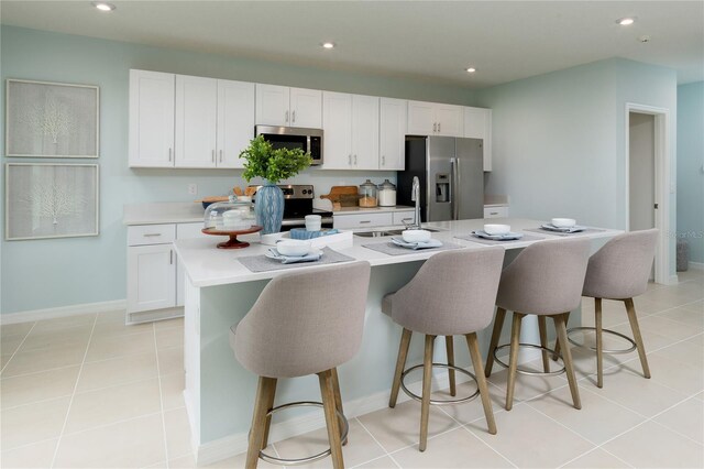 2076 Babbling Brook Blvd, Auburndale, FL 33823 - kitchen featuring appliances with stainless steel finishes, a sink, white cabinets, light countertops, and a kitchen bar